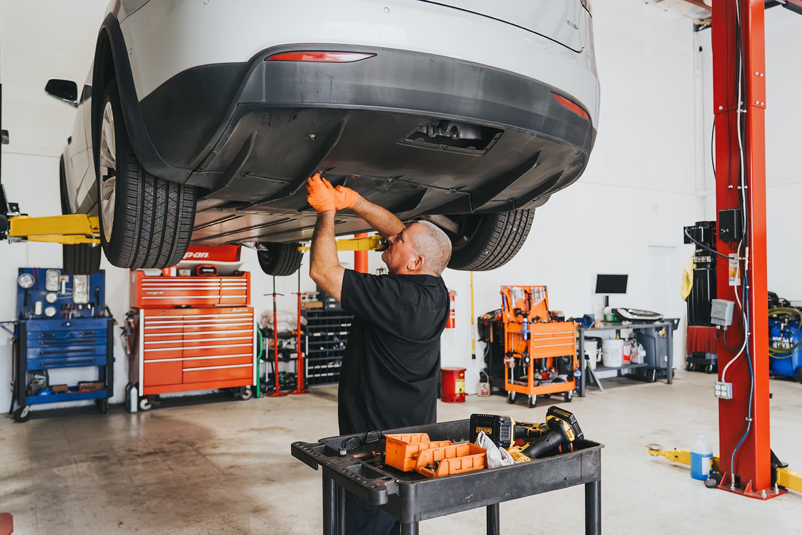 Electrified Garage technician inspecting the underside of a white Tesla in the Orlando shop.