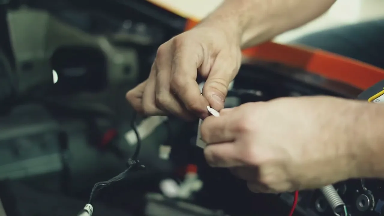 Close view of hands performing electrical and diagnostic work inside the shop.